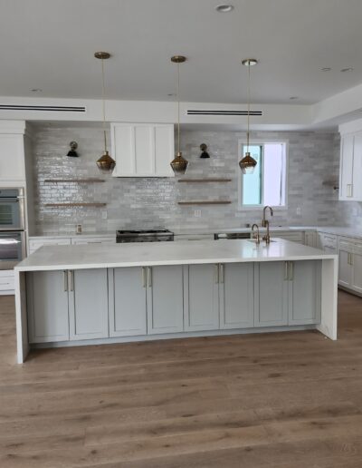 A white kitchen with wood floors and stainless steel appliances.