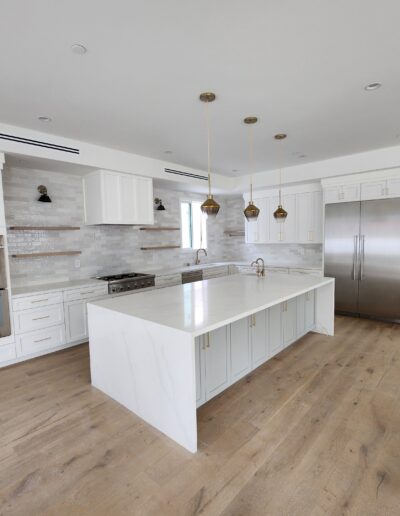 A white kitchen with wood floors and stainless steel appliances.