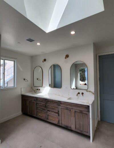 A bathroom with two sinks and a skylight.