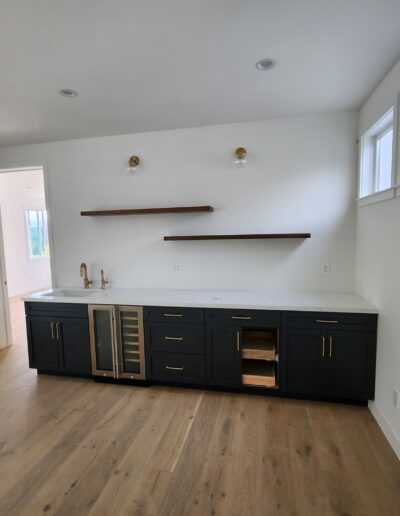 A kitchen with black cabinets and wood floors.